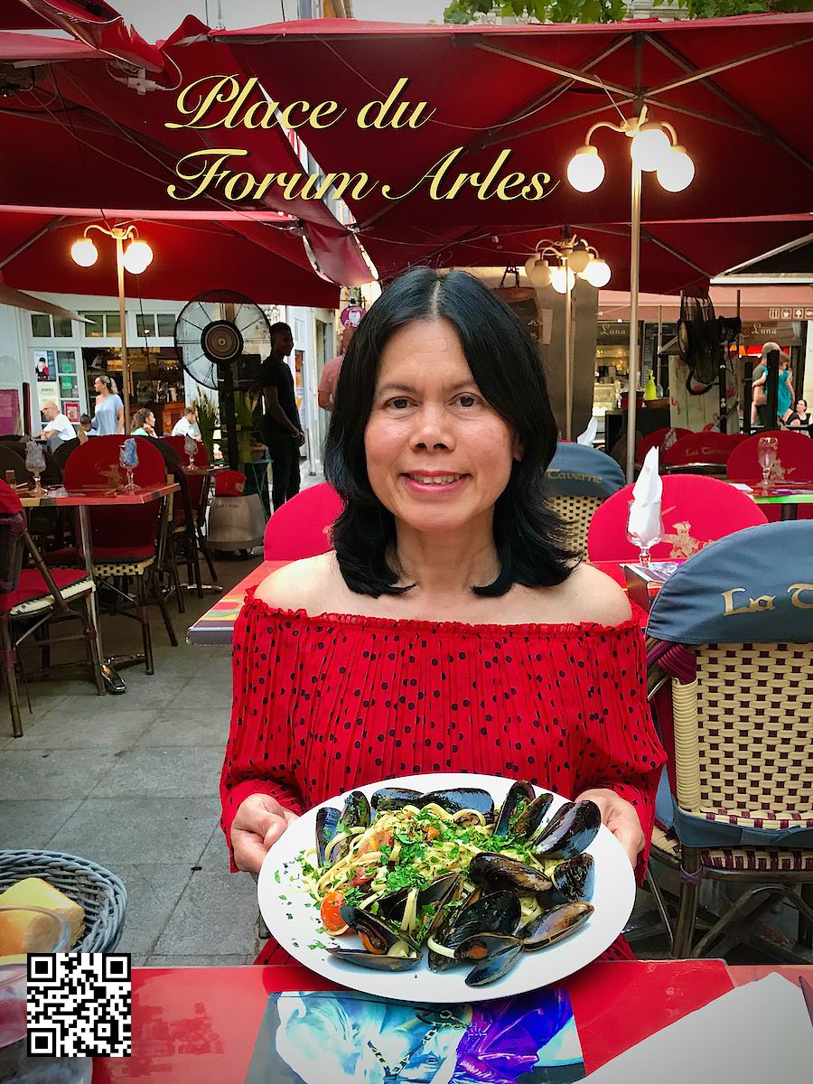 France Provence Arles Place du Forum woman at a restaurant holding a plate of mossels and pasta