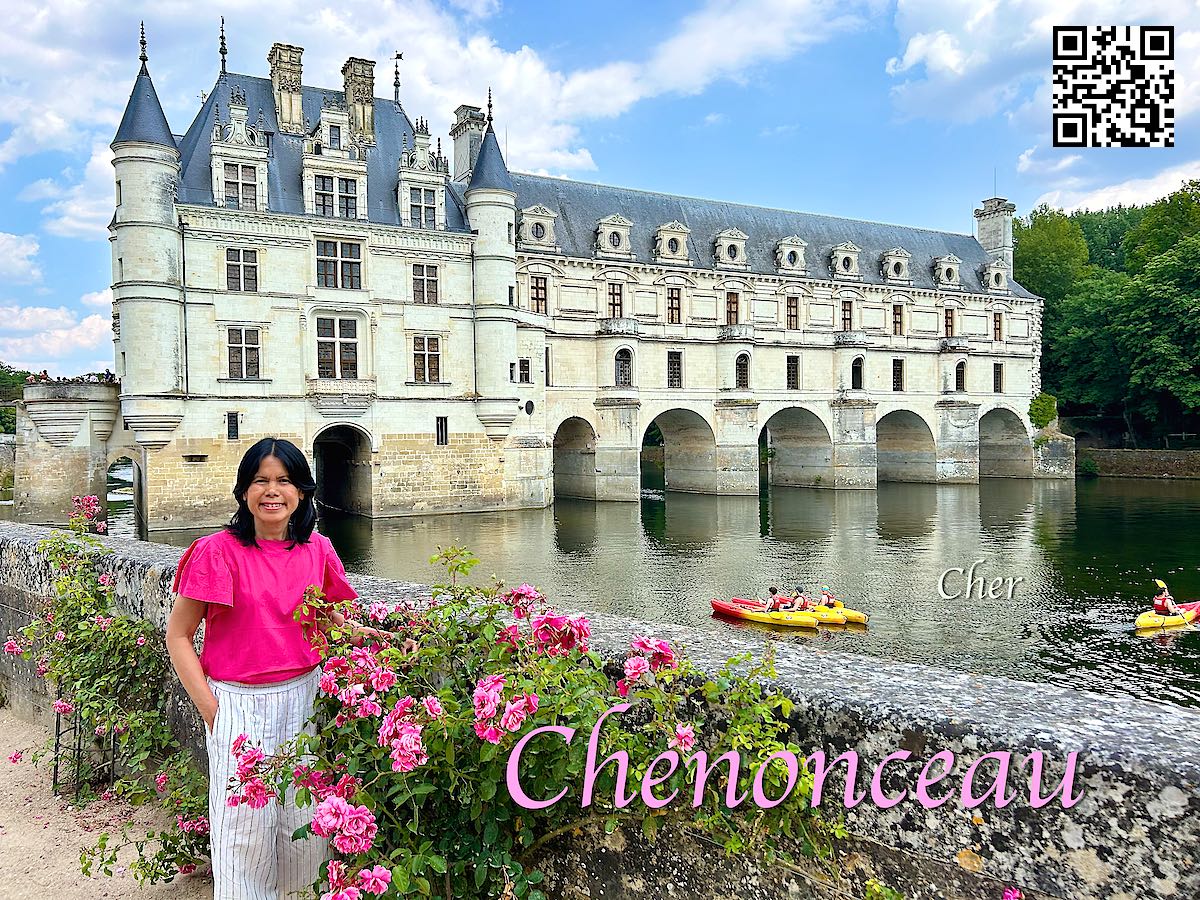 France Château de Chenonceau women in pink in front of the castle and the river Cher next to pink roses