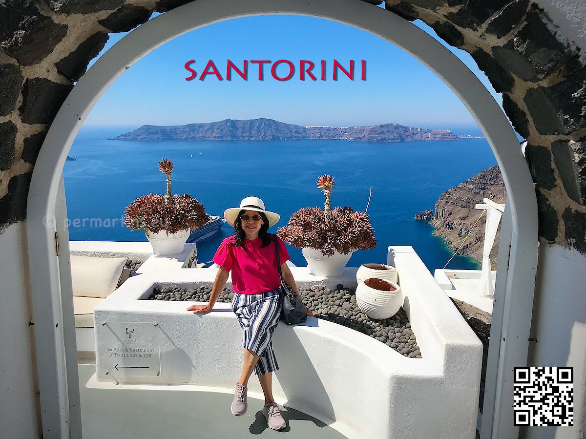 Greece Santorini Firostefani woman with a hat sitting at Dana Villas great view of caldera through an arch