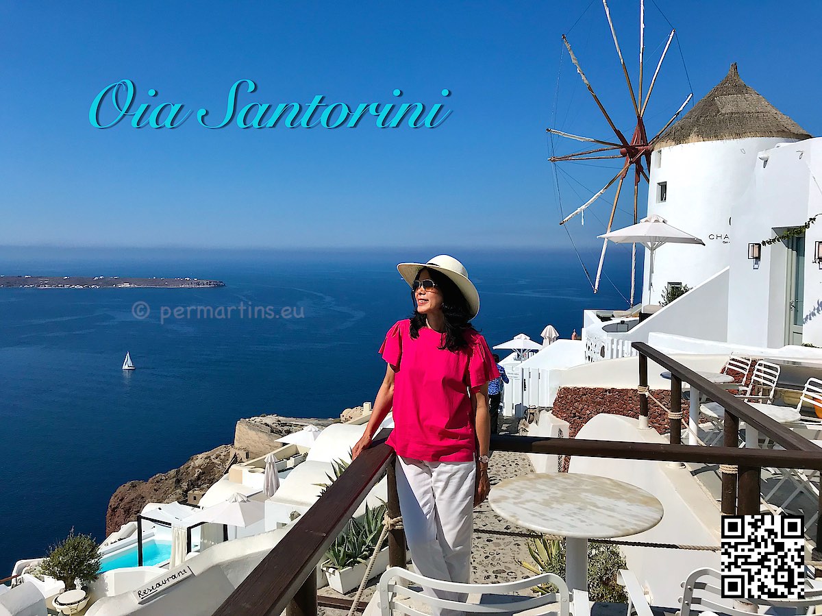 Greece Santorini Oia woman with a hat looking out over the caldera at Sunset Windmill a popular place to watch the sunset
