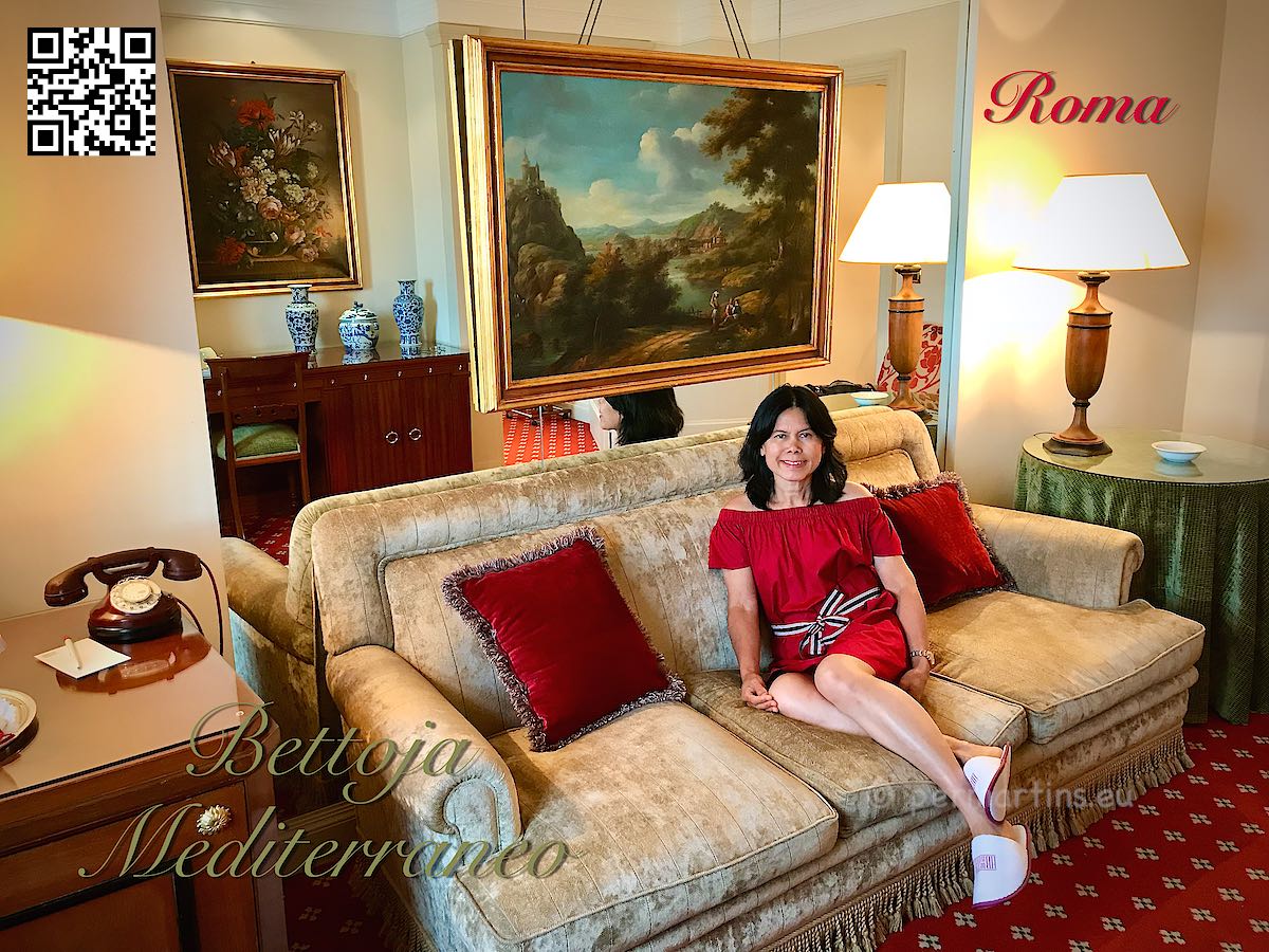 Italy Rome Hotel Bettoja woman in red sitting in a sofa in a suite with paintings