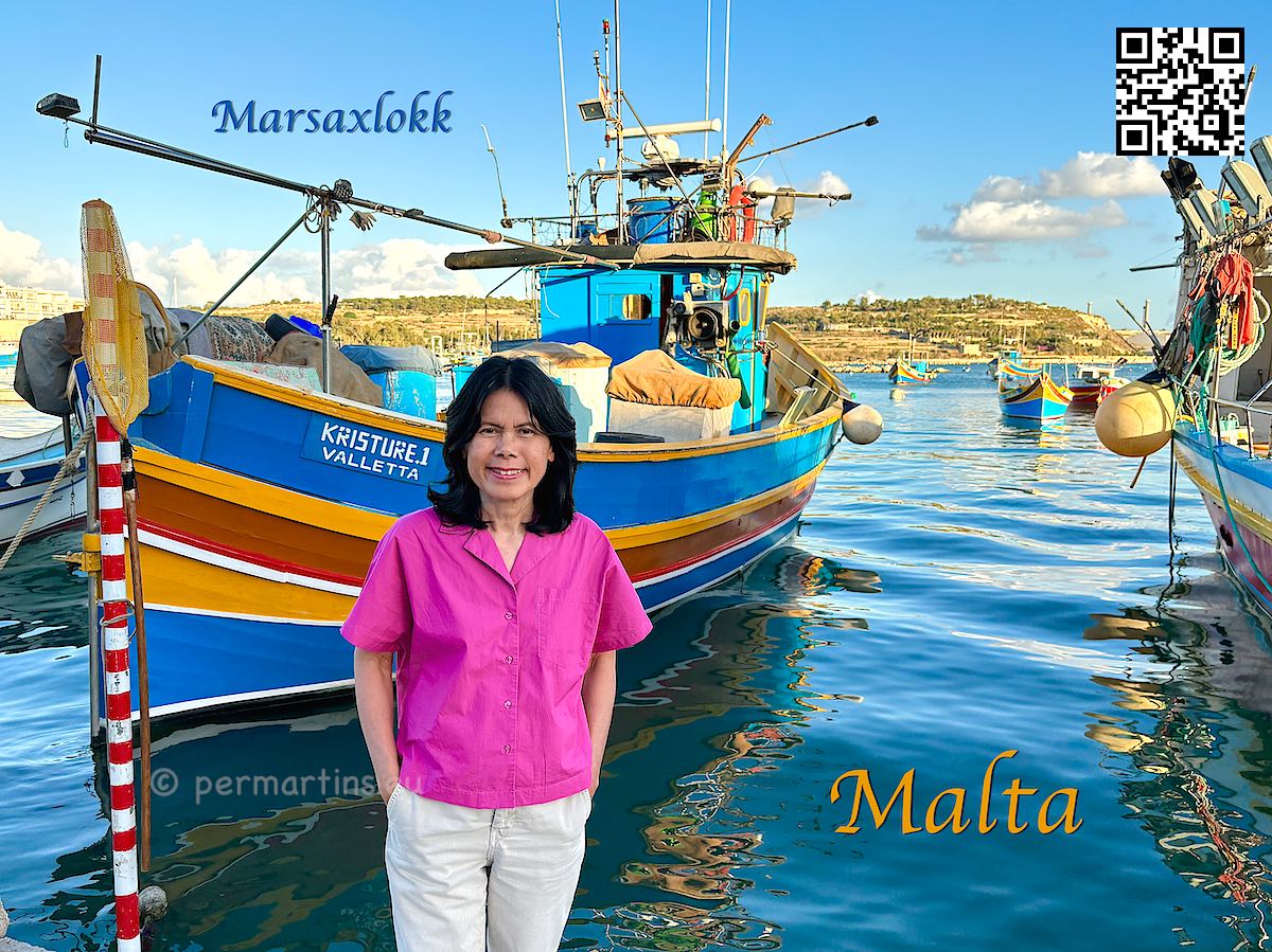 Malta Marsaxlokk woman standing in front of fishing boats