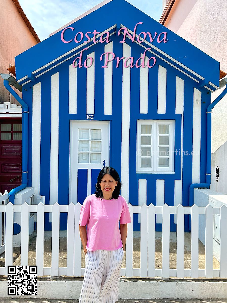 Portugal Costa Nova woman standing in front of a blue and white striped house