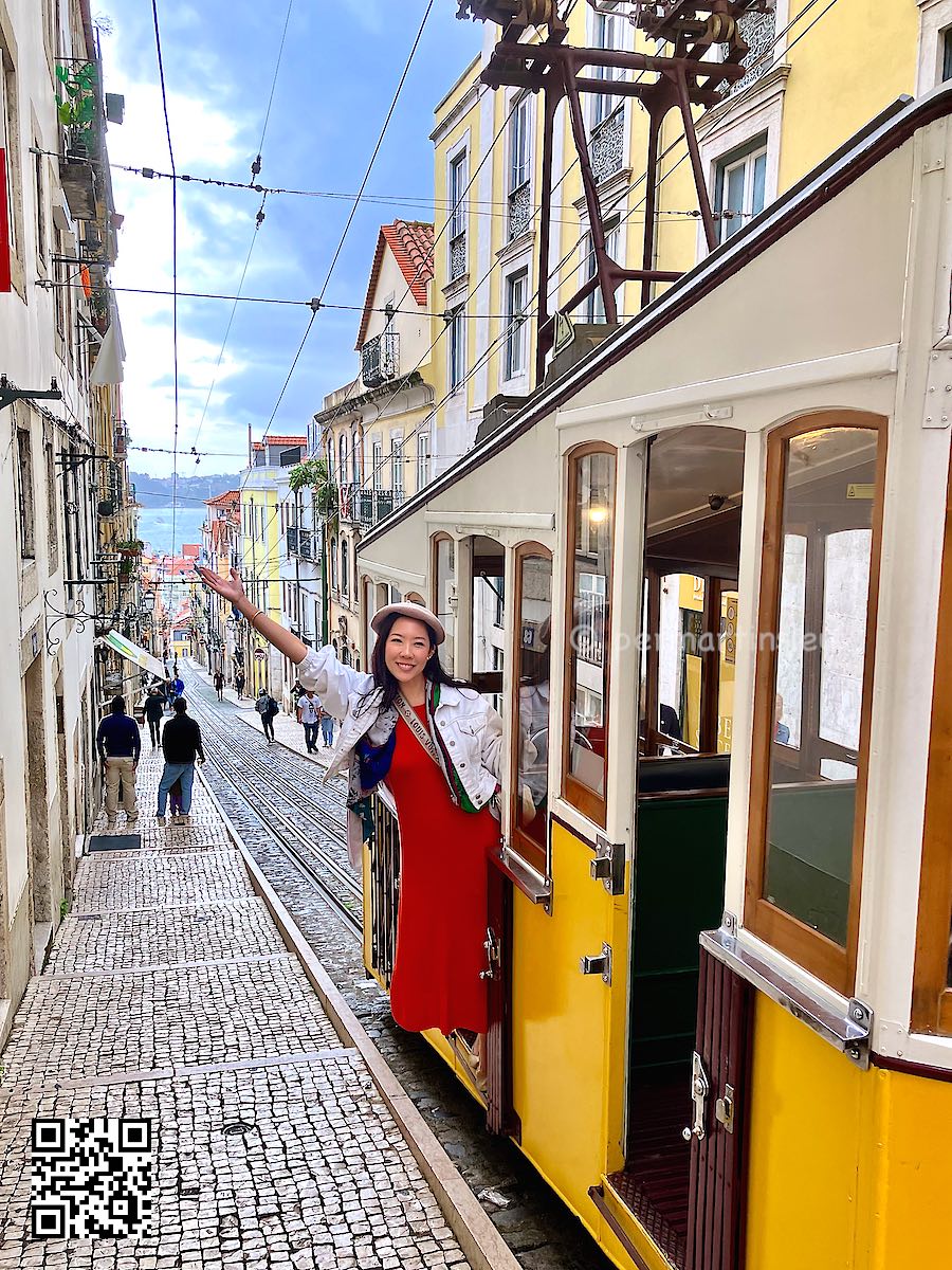 Portugal Lisbon Elevador da Bica yellow tram with a woman leaning outside and waving